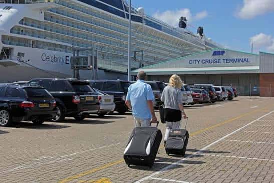 Vista exterior del City Cruise Terminal con un crucero atracado y viajeros con equipaje