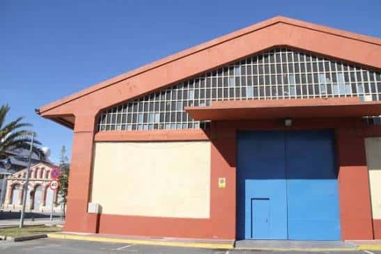Fachada exterior del Refugi 1 del Moll de Costa con puerta azul y cielo despejado