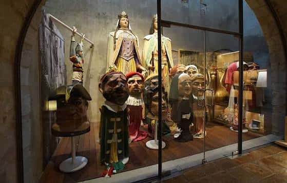 Exposición de cabezas gigantes y trajes tradicionales en vitrina