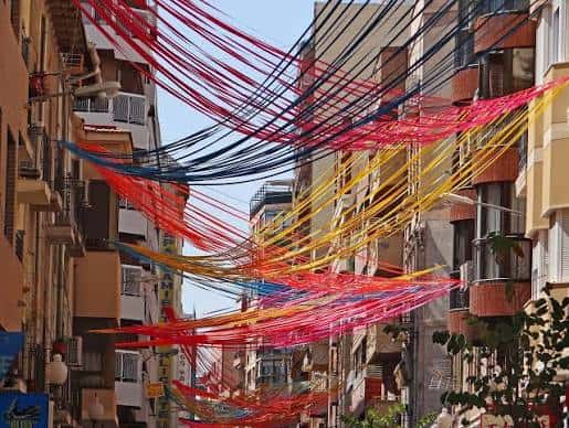 Decoración festiva con cintas de colores colgando sobre la calle