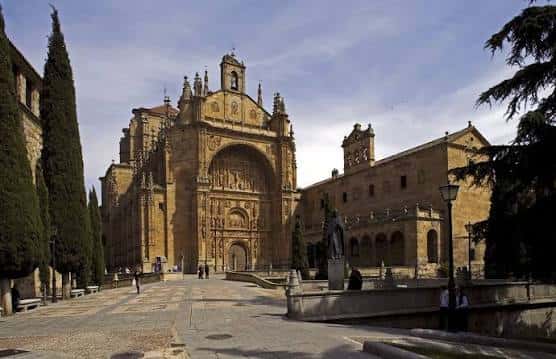 Fachada principal del Convento de San Esteban desde la plaza, con cipreses y cielo despejado