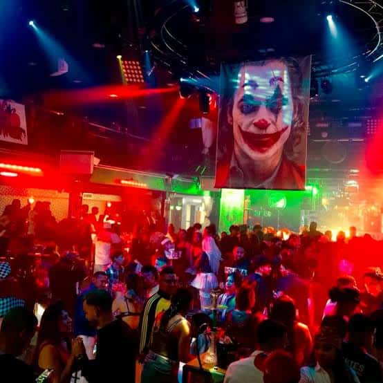 Interior de la discoteca con iluminación de neón y una gran pantalla mostrando una imagen