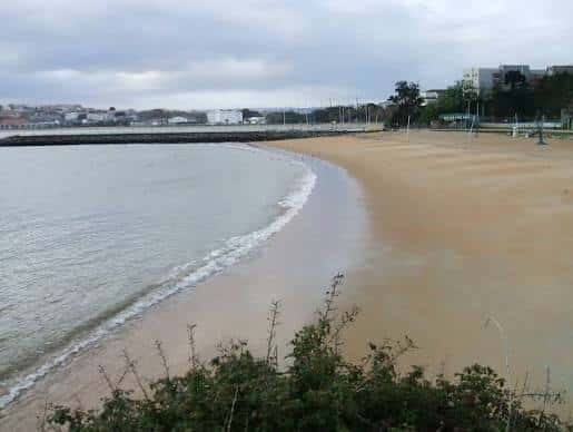 Vista general de la playa en un día nublado con el mar y el malecón