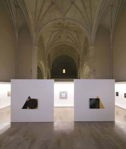 Interior de la nave gótica convertida en sala de exposiciones con bóvedas de crucería y obras de arte contemporáneo