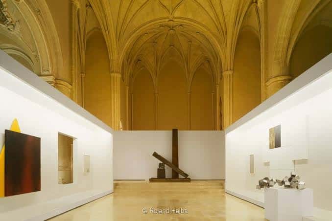 Sala de exposiciones con techos abovedados y esculturas modernas en el centro
