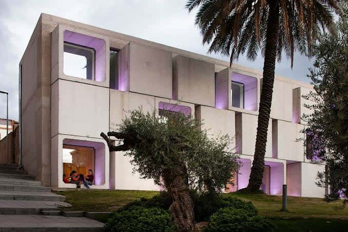 Fachada moderna de la Biblioteca Central Antonio Gala con iluminación púrpura en los ventanales