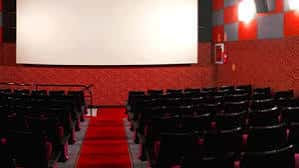 Interior de la sala de cine con butacas negras y alfombra roja
