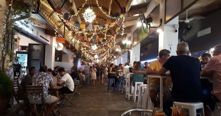 Vista nocturna del interior del mercado gastronómico con iluminación cálida y ambiente festivo