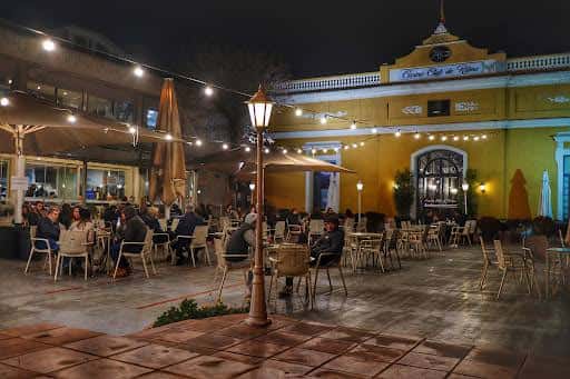 Terraza exterior del Casino Club de Ritme por la noche con mesas, sillas y luces decorativas