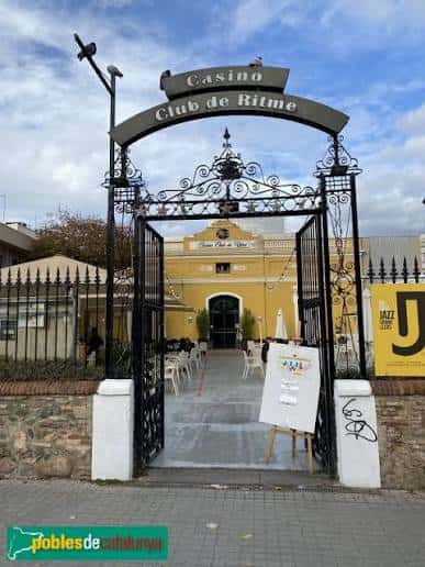Entrada principal del Casino Club de Ritme con arco de hierro forjado y fachada amarilla