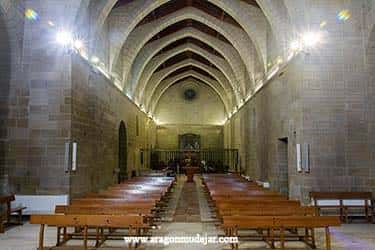 Interior de la iglesia con bóvedas de crucería y bancos de madera para eventos