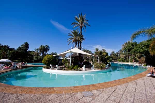 Piscina principal del parque con zona de descanso y toldos bajo cielo despejado