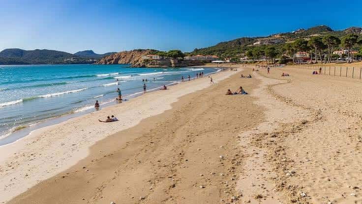Vista panorámica de la playa de Torà con arena dorada y olas suaves