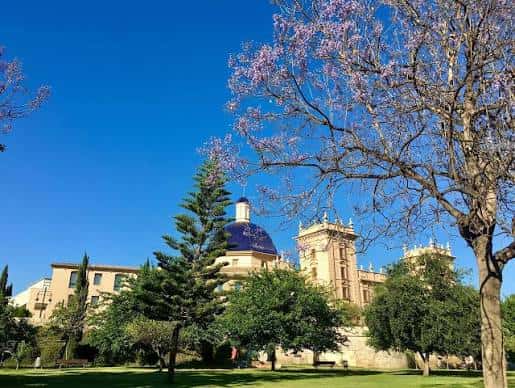 Vista panorámica del Palacio de la Zaidía con su cúpula azul y jardines en primer plano bajo un cielo despejado