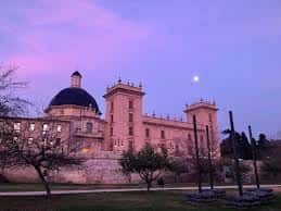 Fachada del Palacio de la Zaidía al atardecer con cielo rosado y luna visible