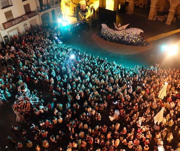 Vista aérea de una multitud congregada en una plaza para un evento nocturno