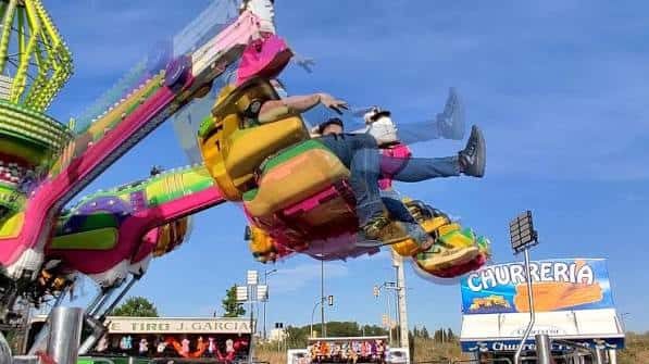 Atracción de montaña rusa en movimiento con cielo azul y letrero de churrería