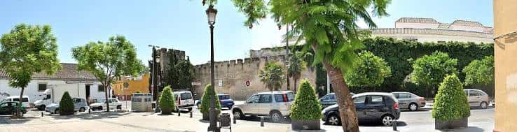 Panorámica de la Plaza de la Merced con murallas y vehículos estacionados