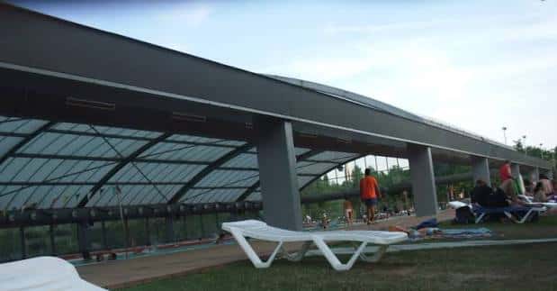 Vista exterior de la piscina cubierta con su estructura de vidrio y metal