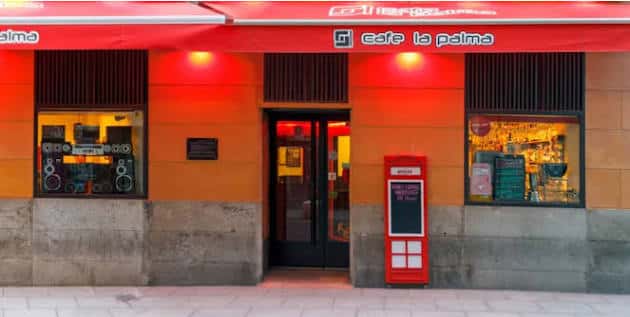 Fachada diurna del Café La Palma con toldo rojo y teléfono británico