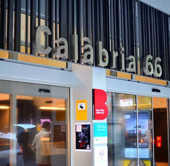 Vista exterior de la entrada principal del Espai veïnal Calàbria 66 con su logotipo en la fachada