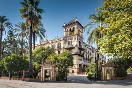 Vista exterior del Hotel Alfonso XIII durante el día con palmeras y portada principal
