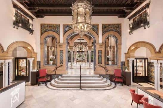 Interior del vestíbulo principal con arcos, azulejos y lámpara de cristal