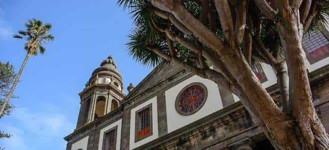 Fachada de iglesia colonial con torre y palmeras