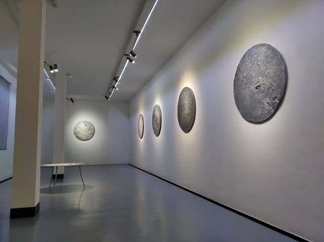Interior de la sala de exposiciones con obras circulares en la pared