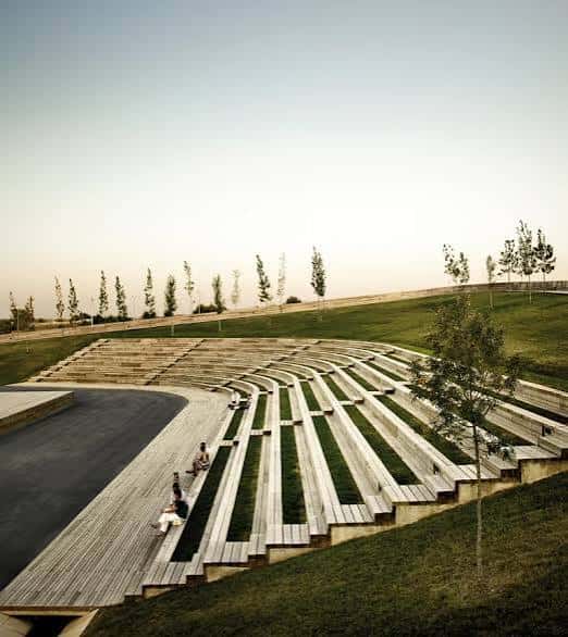 Gradas de madera integradas en la colina con personas descansando