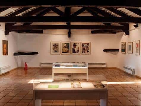 Sala de exposiciones con vigas de madera y obras enmarcadas