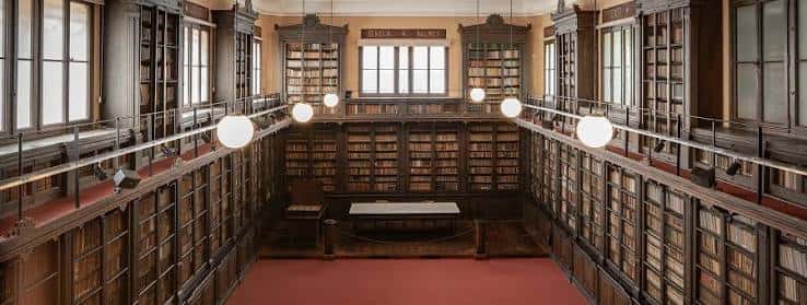 Sala de lectura histórica con estanterías de madera y alfombra roja