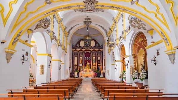 Interior de la iglesia del Convento de San Francisco, con nave central, bancos de madera y retablo barroco