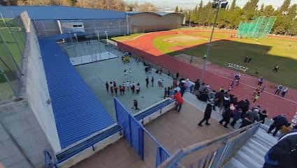 Vista elevada de las instalaciones deportivas exteriores con gradas y pista de atletismo