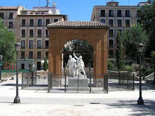 Monumento a Daoíz y Velarde bajo el Arco de Monteleón en la plaza, con arquitectura histórica al fondo