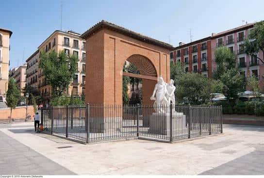 Vista diurna del monumento y el arco histórico en la plaza