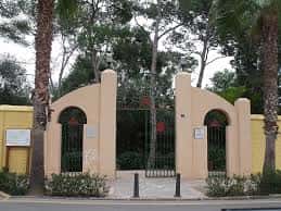 Entrada principal con arco decorativo y palmeras al frente, acceso a la plaza o recinto cultural