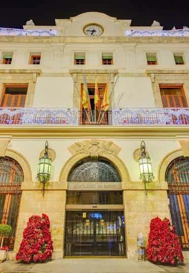 Fachada del Ayuntamiento de Sagunto iluminada por la noche con decoración festiva