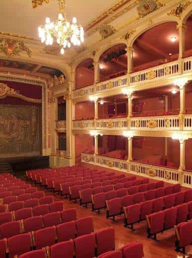 Ángulo lateral del teatro que destaca los detalles arquitectónicos y la iluminación cálida