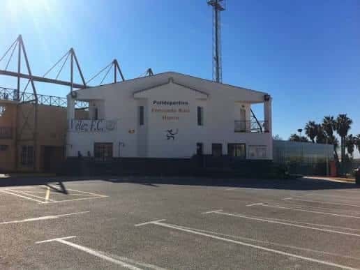 Fachada principal del Polideportivo Fernando Ruiz Hierro con estacionamiento frente a él