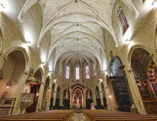 Vista interior de la nave central de la Iglesia Prioral de San Pedro con bóvedas de crucería y bancos de madera