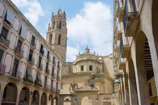 Vista de la torre y fachada de la Iglesia Prioral de San Pedro desde la plaza con arcos coloniales