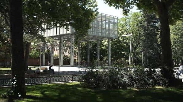 Estructura de cristal y acero en el parque rodeada de árboles