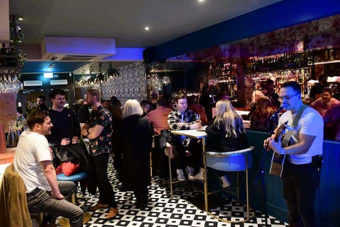 Interior animado del lounge con clientes disfrutando de música en vivo y ambiente social