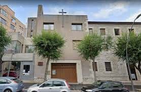 Fachada principal de la iglesia con entrada de madera y árboles frente al edificio