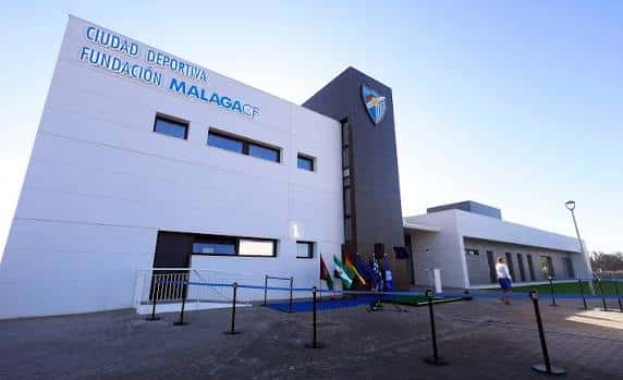 Fachada principal de la Ciudad Deportiva Fundación Málaga CF con letrero visible y cielo despejado