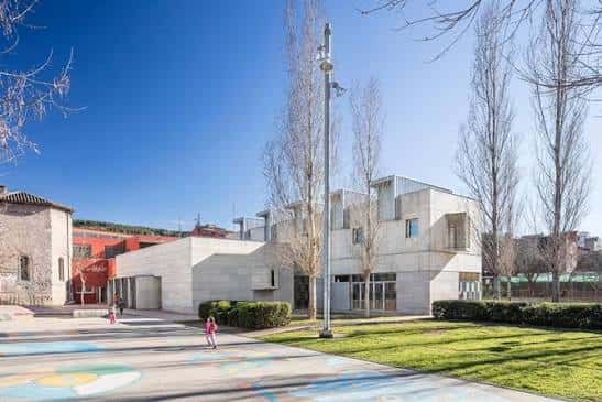 Vista exterior moderna del centro cívico con arquitectura en hormigón y espacio verde
