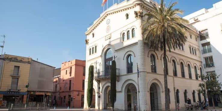 Fachada principal de la Casa de la Vila en Badalona con palmeras y cielo despejado