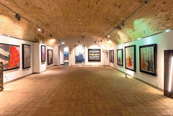Galería de arte con bóveda de cañón y obras expuestas