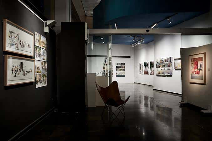 Vista del interior de la galería con una silla y obras de arte en las paredes
